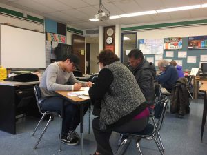 student sits at desk with two residents