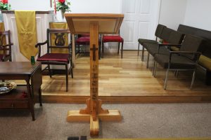 podium built of wood with a cross on the front of it, chairs alongwide of it