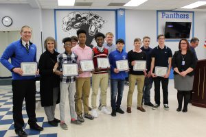 The Monticello Boys Cross Country team poses and smiles holding their Scholar Athlete certificates