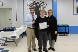 Board Award recipient Cheryl Hampel  poses and smiles as she holds the certificate she received at the Board Awards ceremony 