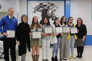 The Monticello Girls Cross Country team smiles and poses together after being presented with the Scholar Athlete distinction 