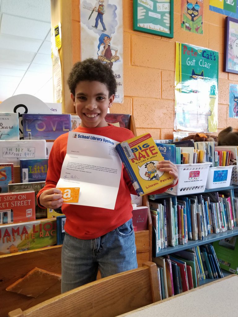 George L. Cooke Elementary School student Jalon Fennell poses with the Amazon gift card that he won by participating in the Cross County Reading Challenge