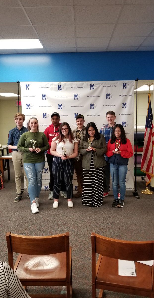 eight students who received the student of distinction honor stand in front of a back drop