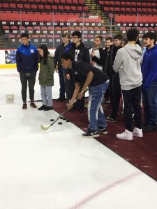 One student takes a shot on the ice with a hockey stick