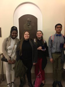 Reannon Matulewich, Noel Varughese, Madison Fields, Courtney Travis stand next to each other against a wall at the Malcolm Bump Debate Tournament