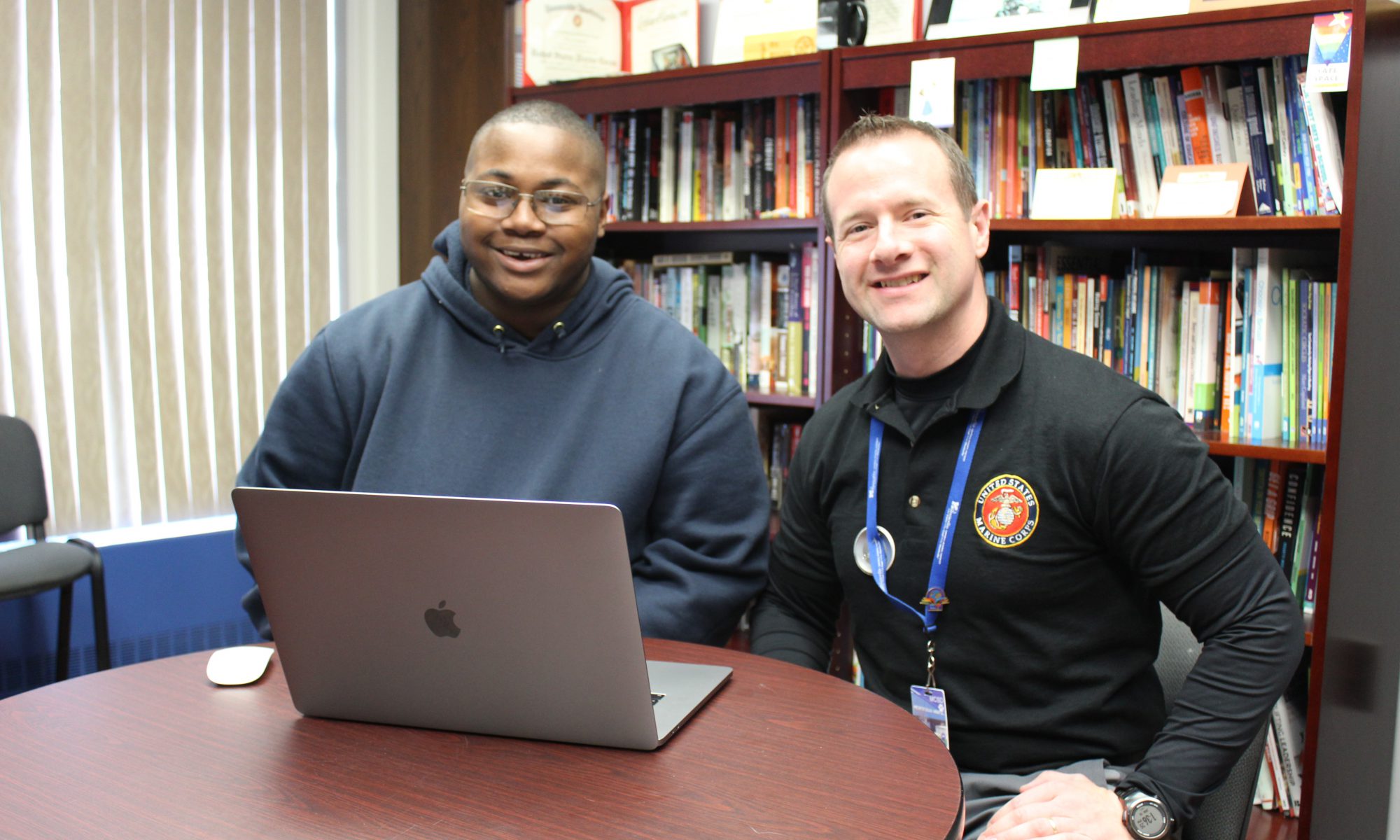 Principal Stephen Wilder and student Tylan Williams sit at a desk with a computer in front of them, smiling