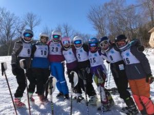 a group of skiers pose on top of a mountain