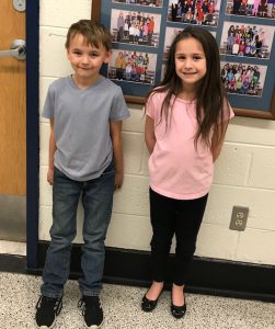 two students stand in the hallway smiling