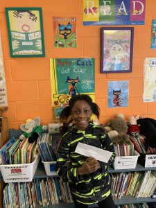 Fifth-grade student Kamsiyonna Dim holds the certificate she won as part of the Cross COuntry Reading Challenge