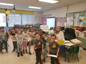 Kindergarten teacher Jennifer Somers sits at her desk surrounded by students 