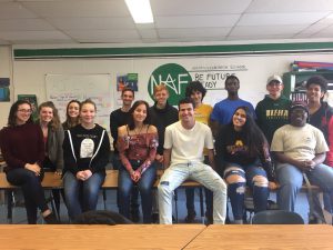 a group of students from the VITA program sit on a table and smile 