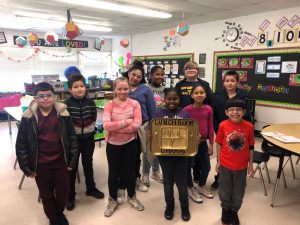 Ms. Boardman's class poses as a group in the classroom holding the golden lunch tray as a symbol of their award