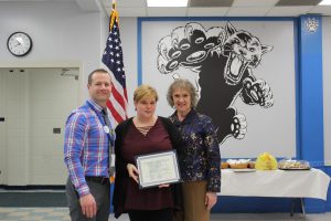 Marie Schall stands holding her Board Award Certificate in the RJK cafeteria with Stephen Wilder and Lori Orestano James