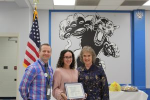 Molly Garcia stands and holds her Board Awards certificate 