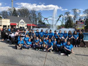 students attending the Music in the Parks competition pose near a fountain. They are all wearing blue shirts