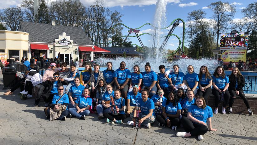 students attending the Music in the Parks competition pose near a fountain. They are all wearing blue shirts