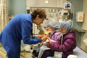 a nurse bends down to talk to students in a hospital room 