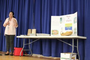 Woman at left talking with visuals on the table at right about Meals on Wheels.