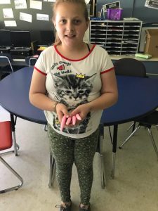 a female student stands and holds hand made candles 