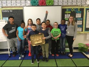 Ms. Nunziata's class stands in the classroom, one boy is holding a gold lunch tray