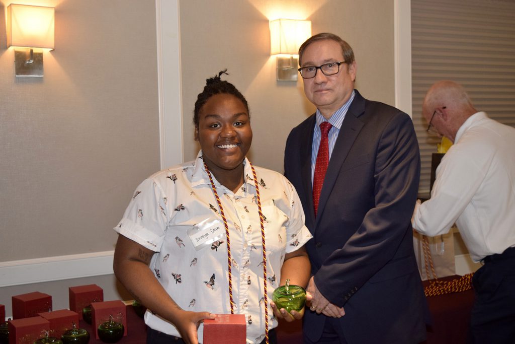 Young woman smiling holding a red box, standing next to a man in a suit