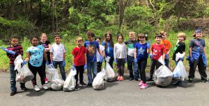 students stand in a line holding bags of garbage