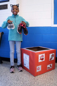 a student holds up two pairs of shoes 