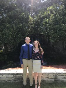 Aiden Johnson stands with Sarah Grodin in front of a fountain 