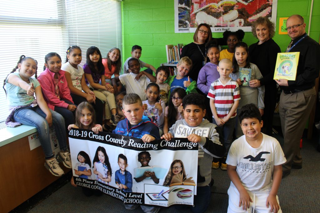 a group of students are holding a banner and a book in the library