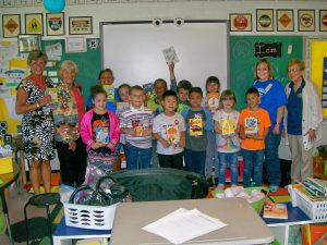 Students in Ms. Shopes class stand together smiling and holding books