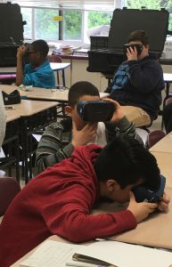 Three students looking through virtual reality goggles