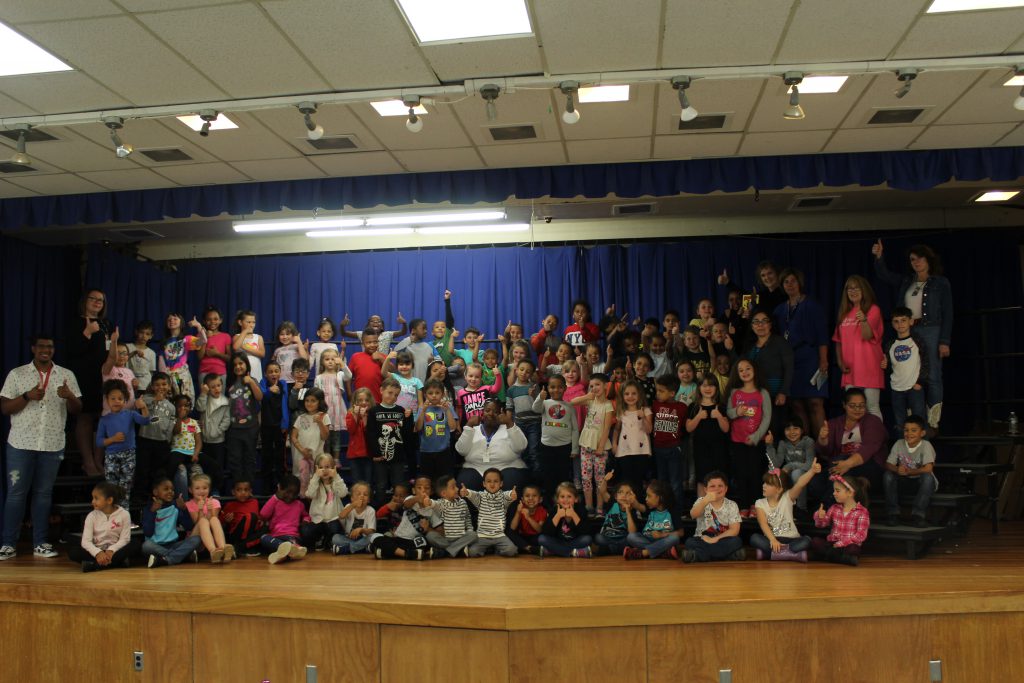 A large group of students stand on stage 