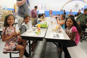 a group of students are sitting at a lunch table