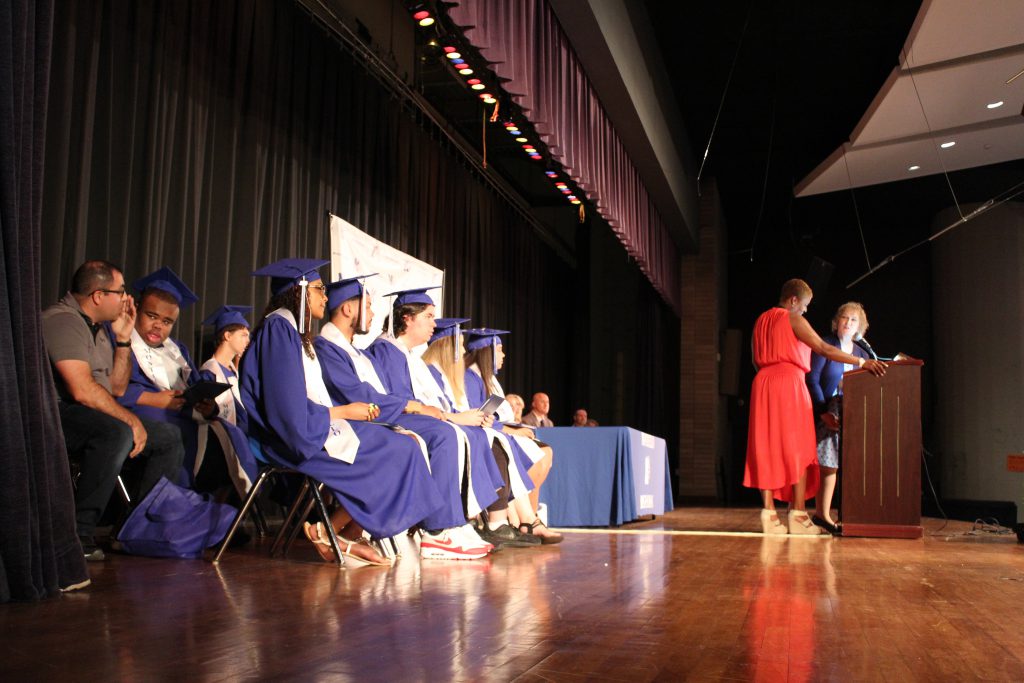 The nine graduates sit on stage during the August ceremony