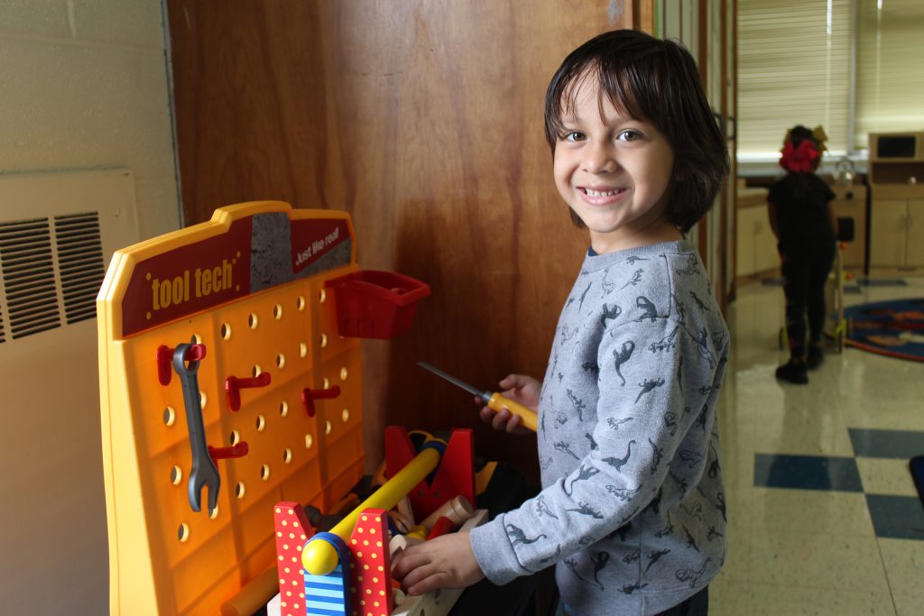 a boy plays at a minature tool station 