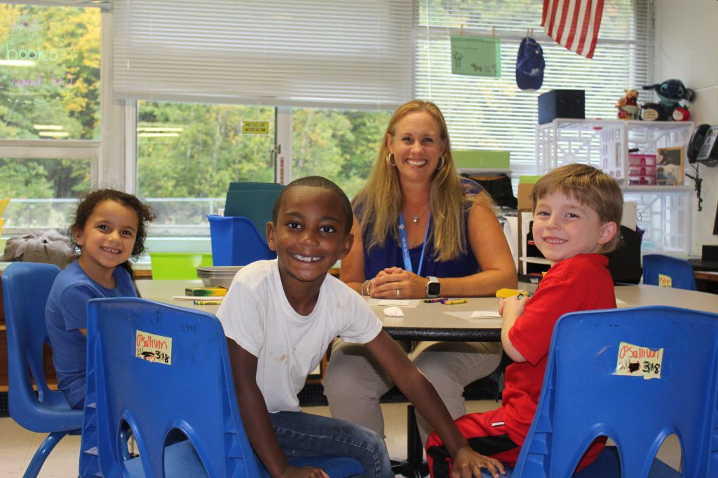 School Counselor Molly Messina sits at a table surrounded by three students 