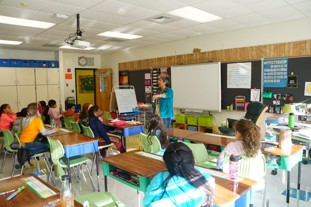 teacher Elisa Mendels stands in front of a class of students 