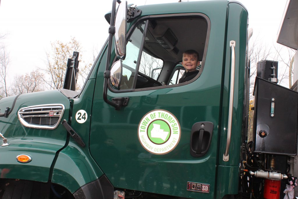 a student grins as he pretends to drive a truck 