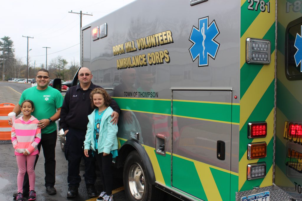 two students and two EMS workers standing next to ambulance 