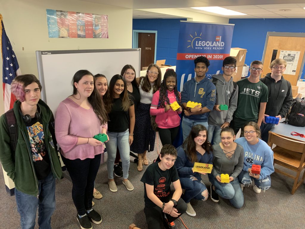 students pose with Marcela Folkl in front of a legoland banner 