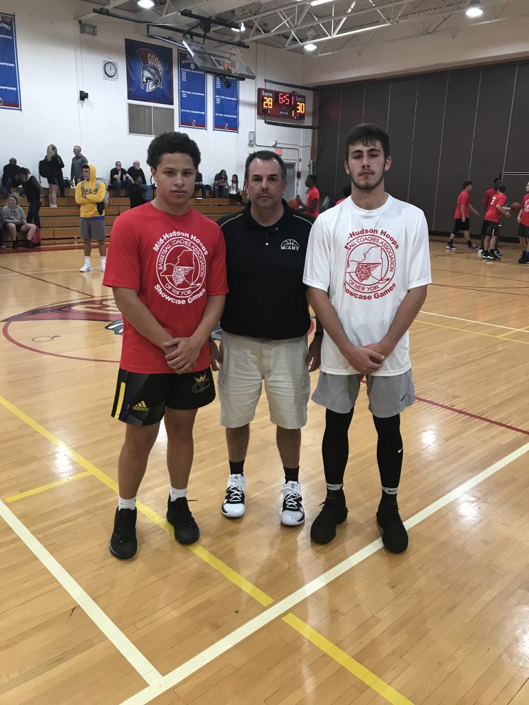 Coach stands in center of two high school basketball players