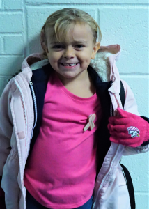 a young girl in a pink shirt smiles 