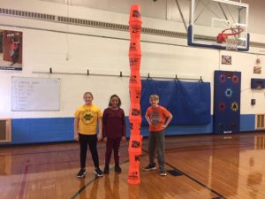 three students stand next to a tower they made in Mrs. Coney's physical education class 