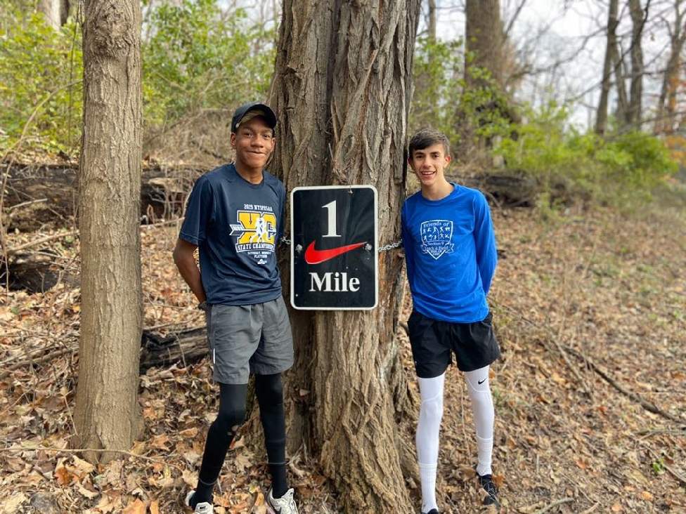two runners pose by a tree 