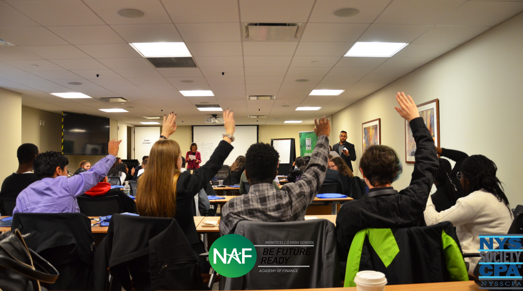 Academy of finance students raise their hands in a classroom 