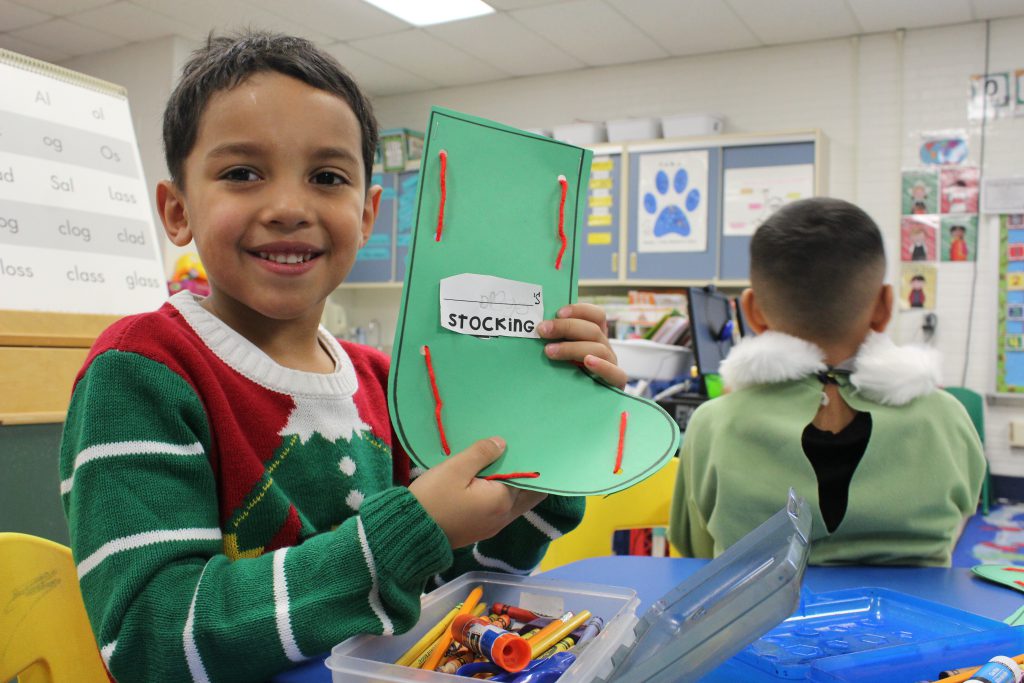 a kindergarten student holds up a craft 