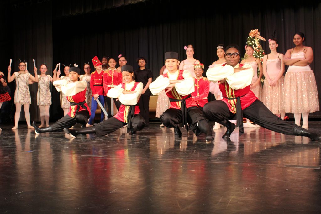 student dancers from the high school's production of the nutcracker are standing on stage