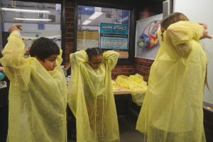 two younger students are putting on safety equipment 