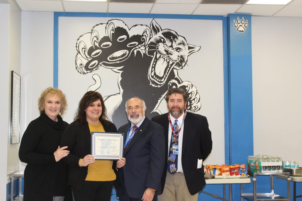 Jenn stands with the Board President Superintendent and Principal holding her certificate 