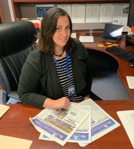 Courtney Bonfante is seated at a desk with copies of the Panther Post in front of her 